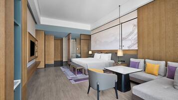 Una habitación de hotel moderna con cama, sofá, escritorio y televisor.