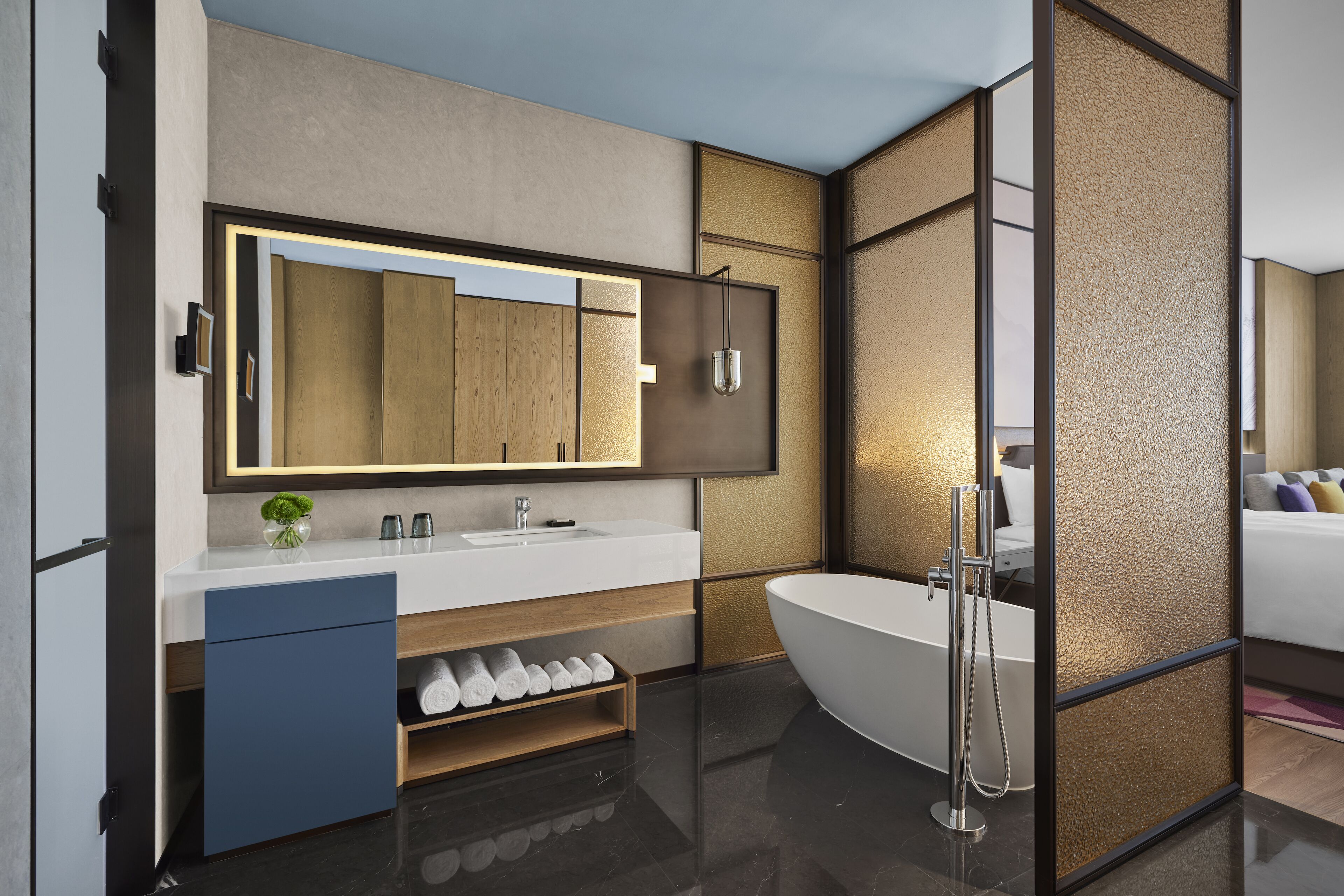 A modern bathroom with a large mirror, a white sink, a freestanding bathtub, and a towel rack.