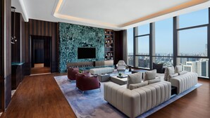 Ein modernes Wohnzimmer mit großem Fernseher, Sofas und Blick auf die Stadt.