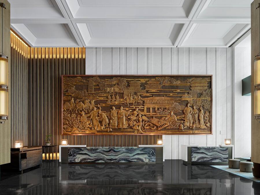 A reception area with a large carved wall, polished floors, and modern lighting fixtures.