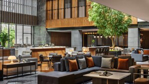 Un moderno vestíbulo de hotel con un amplio espacio para sentarse, un bar y un comedor.