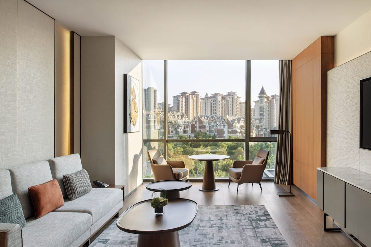 A modern living room with a sofa, two round tables, and a TV on the wall.