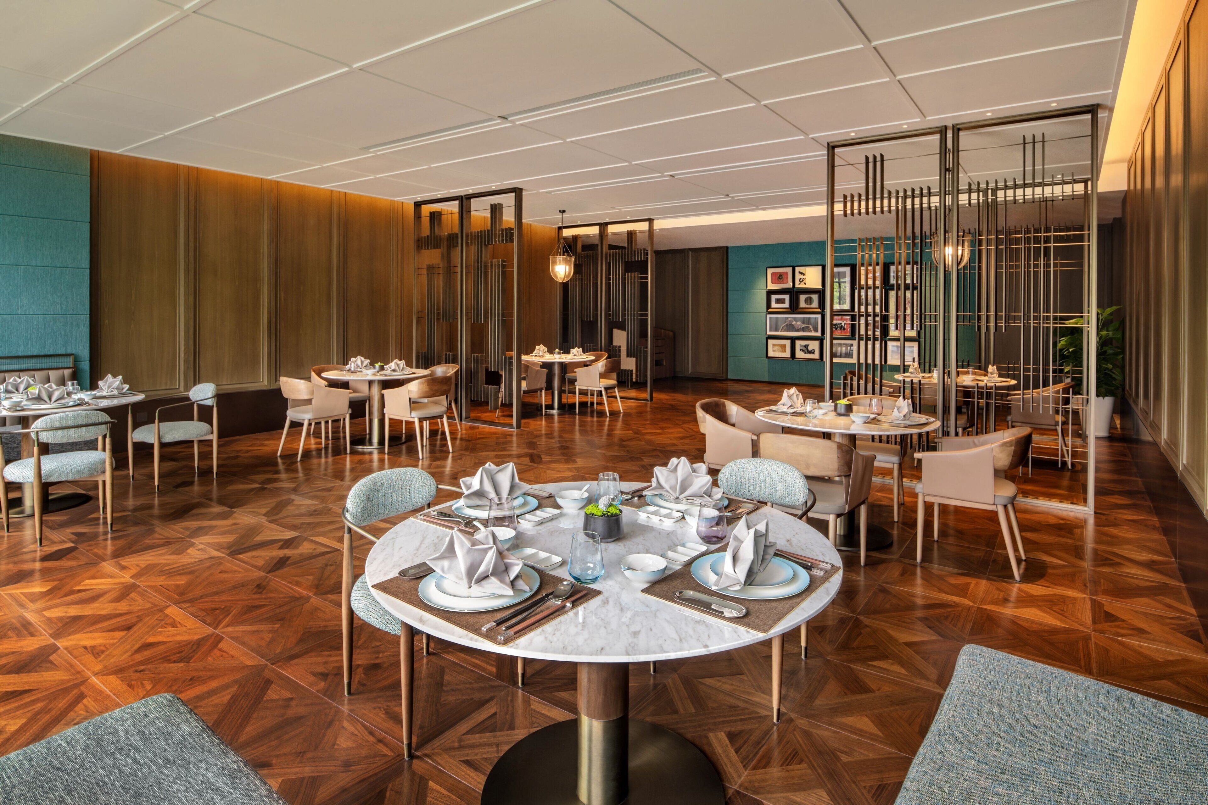 A modern dining area with round tables, chairs, and a central decorative piece.