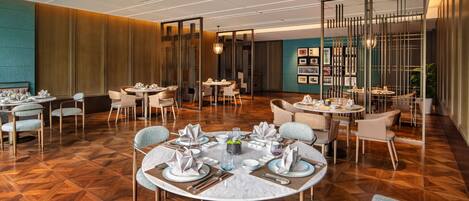 A modern dining area with round tables, chairs, and a central decorative piece.