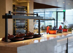 A modern kitchen counter with a stainless steel rack holding several brown pots and pans. - Sheraton Xuzhou (Xuzhou)