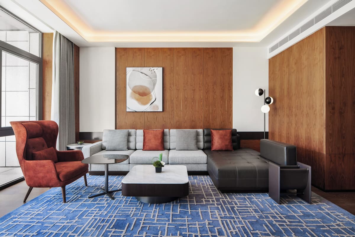 A modern living room with a sectional sofa, a red armchair, a coffee table, and a large window.