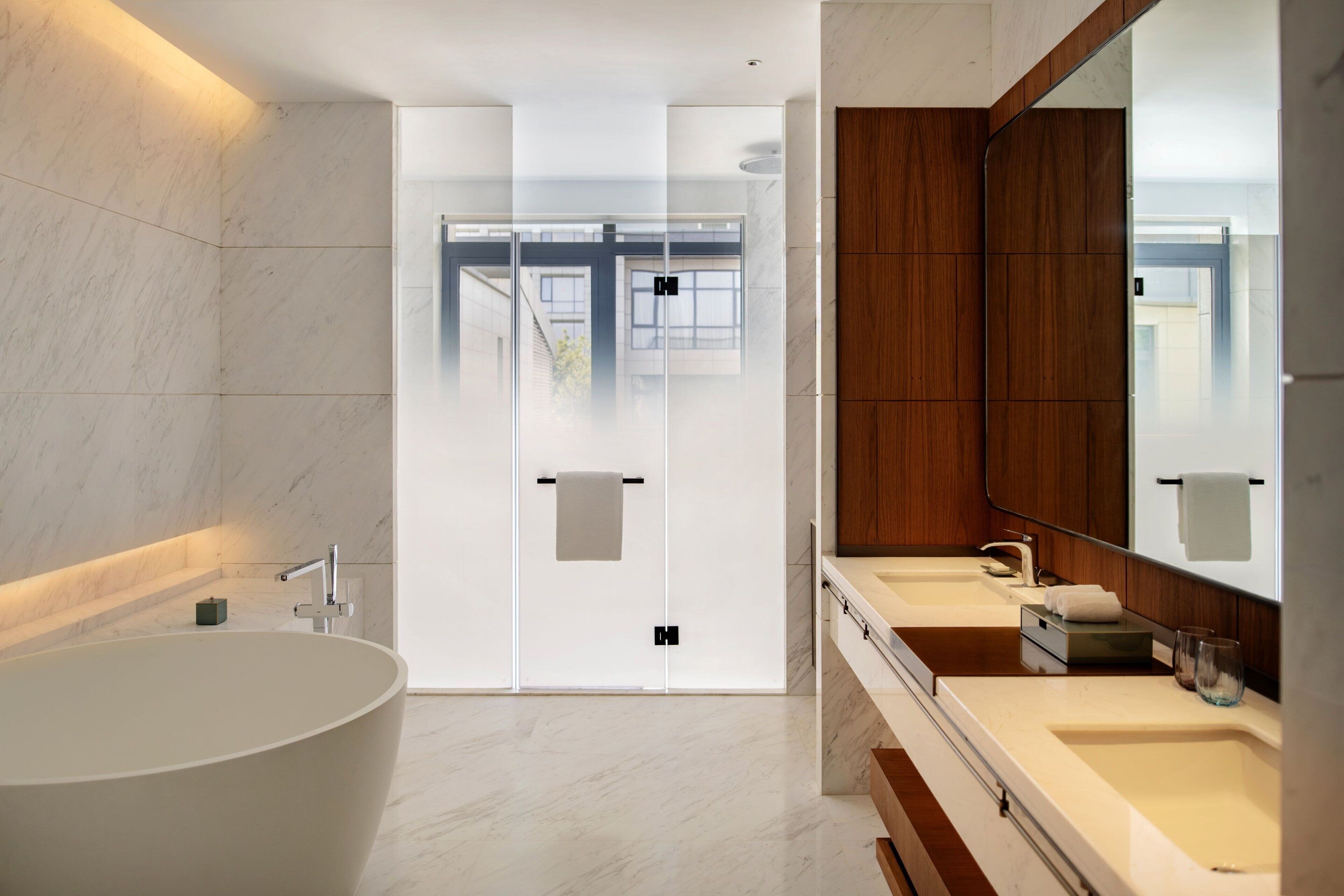 Une salle de bain moderne avec une baignoire sur pieds, deux vasques et un grand miroir.