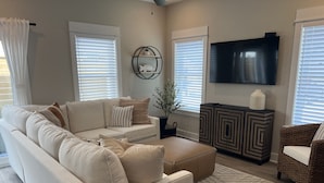 A living room with a beige sofa, a coffee table, a TV, and a patterned rug. - EXCEPTIONAL LOCATION - LUXURY VILLA STEPS AWAY FROM THE BEACH AND POOL (Corolla)