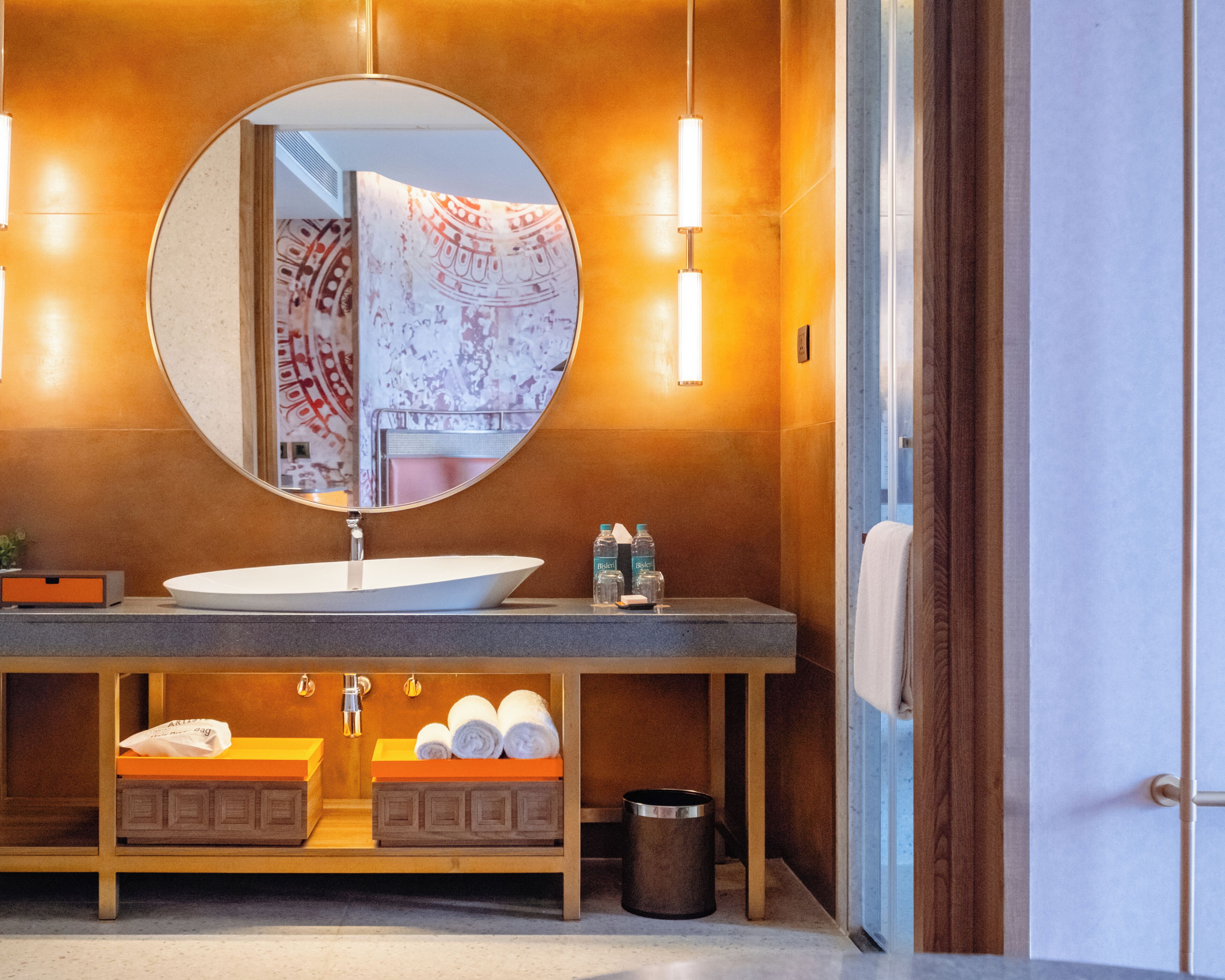 A modern bathroom with a round mirror, a white sink, and a towel rack.