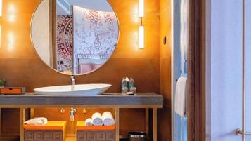 A modern bathroom with a round mirror, a white sink, and a towel rack.