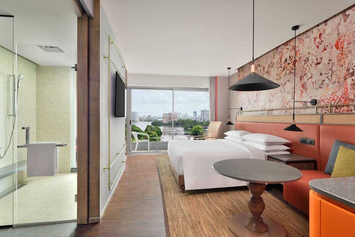 Une chambre d’hôtel moderne dotée d’un grand lit, d’une petite table, d’un canapé, d’une télévision et d’un balcon offrant une vue sur la ville.