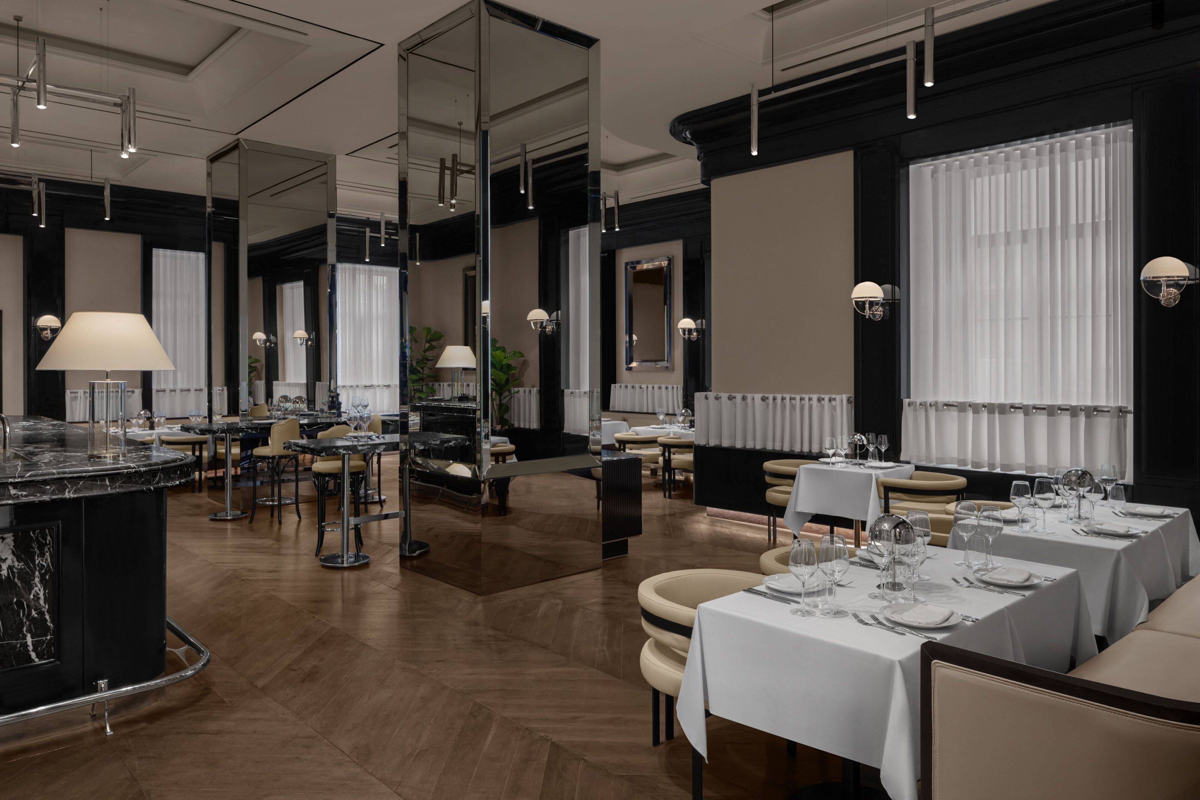 Ein modernes Restaurant mit Marmorarbeitsplatten, mehreren Esstischen und Pendelleuchten.