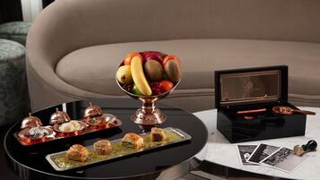 A dining table with a fruit bowl, dessert trays, and a black box with a framed photo and a pen.