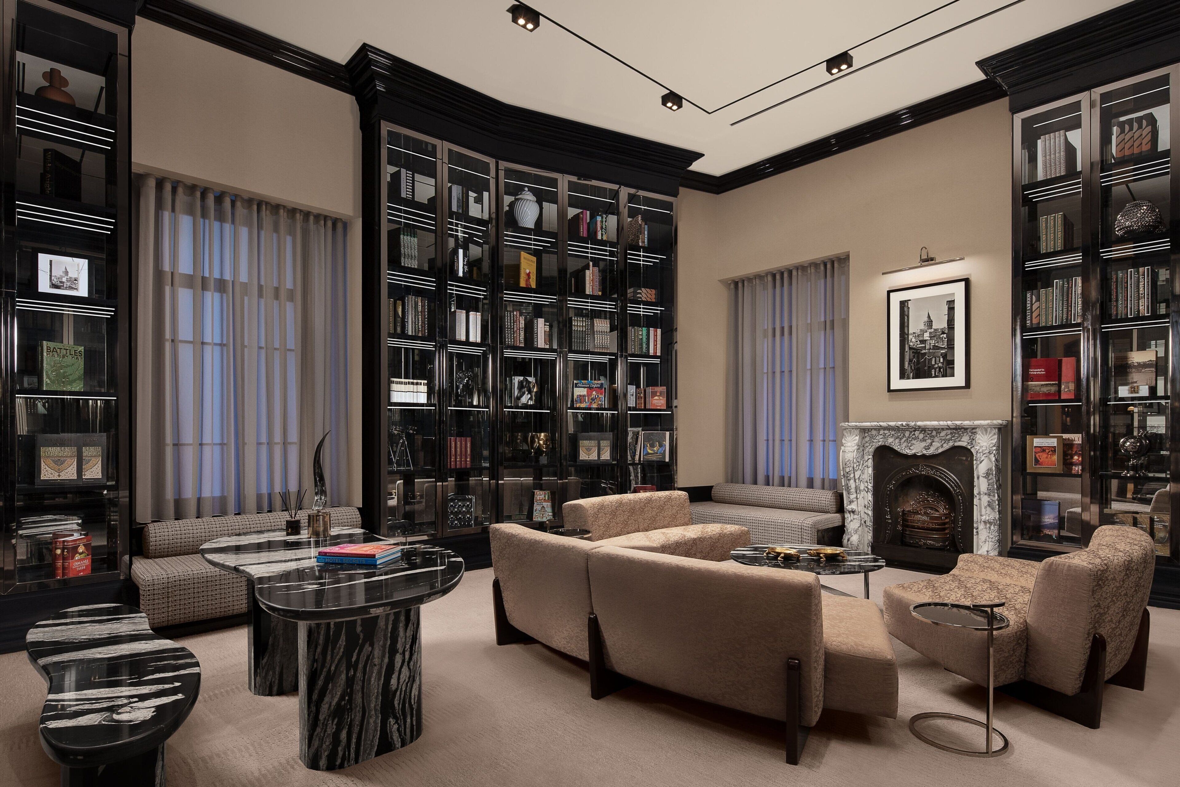 A library with bookshelves, a fireplace, and seating areas.