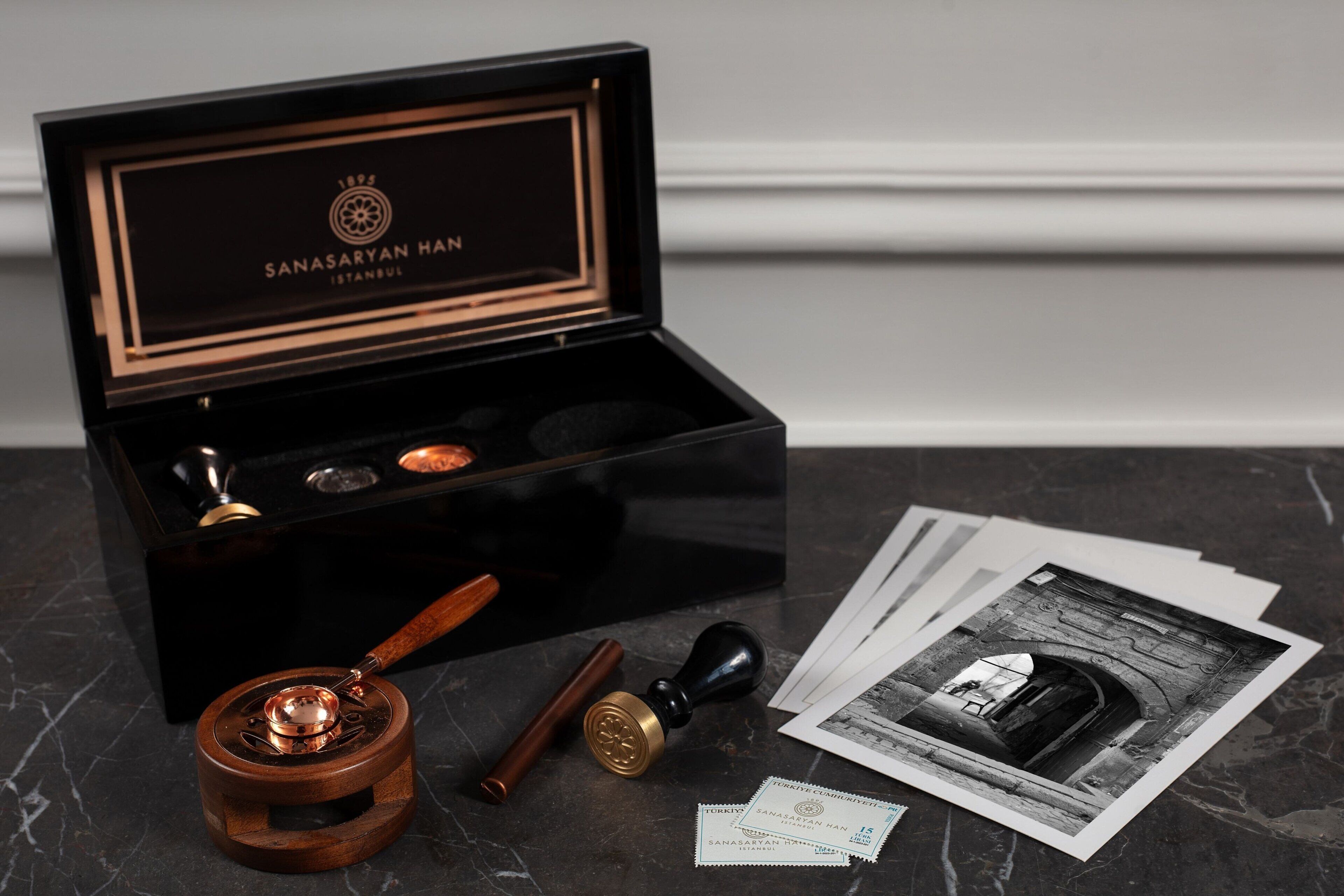A black box with a wooden handle, a stamp, and a few documents on a marble surface.