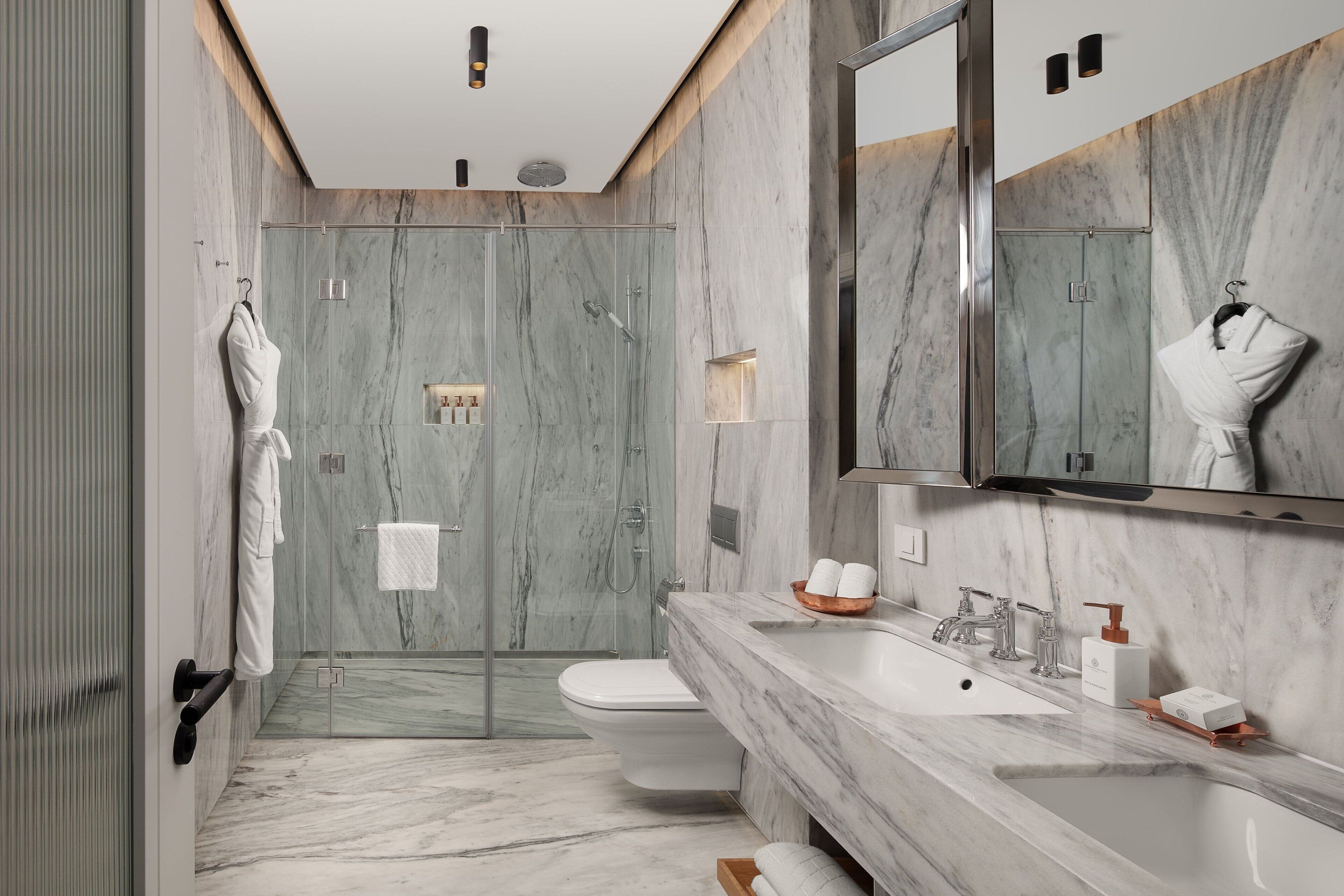 A modern bathroom with a glass-enclosed shower, a marble sink, and a large mirror.