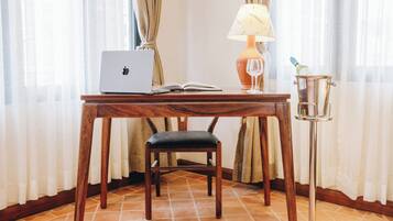 A wooden desk with a laptop, an open book, a wine glass, and a champagne bottle on a table.