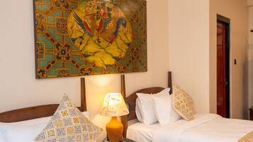A hotel room with two beds, a nightstand with a lamp, a telephone, and a large decorative painting on the wall.