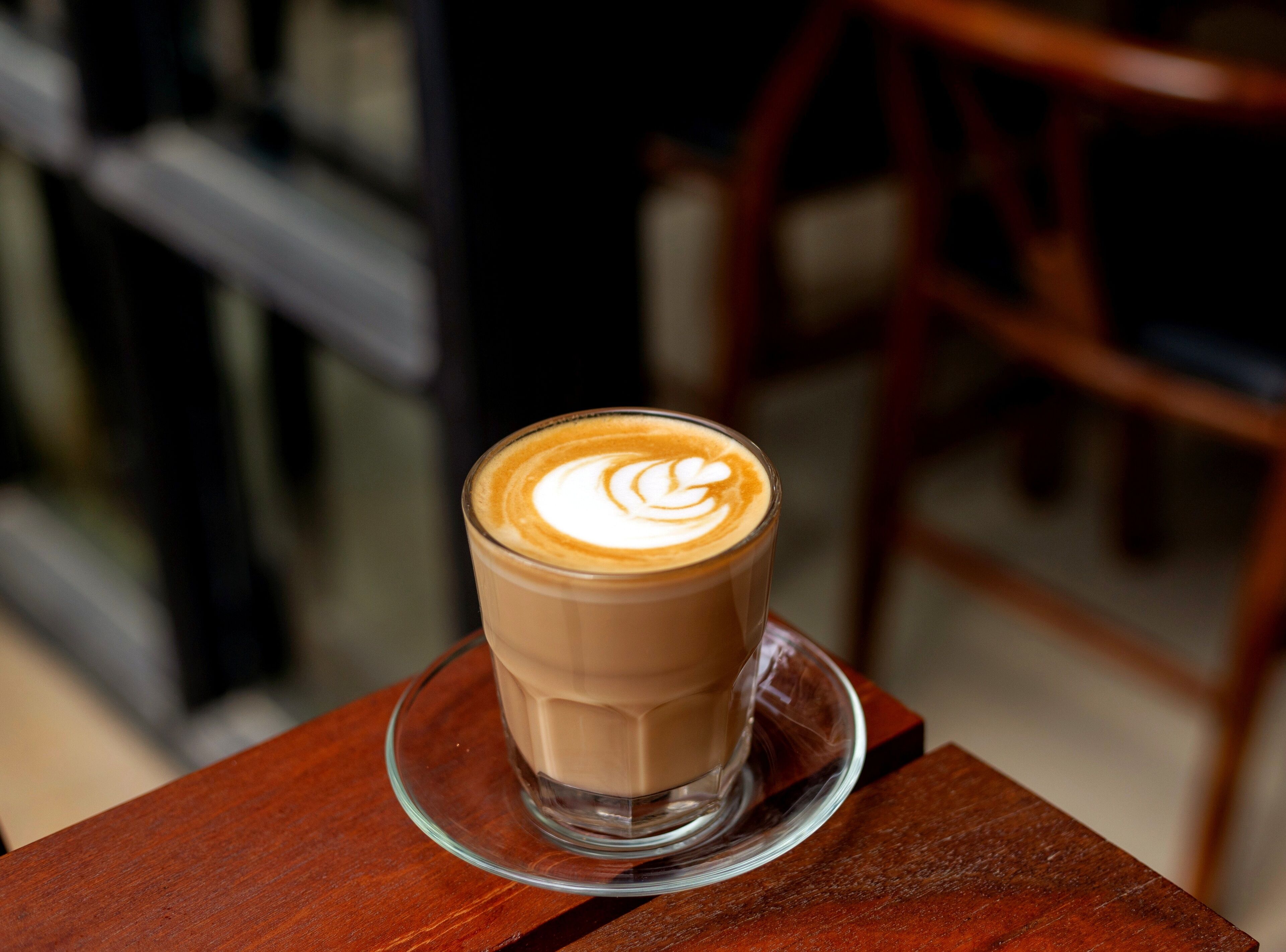 Een kop koffie met latte-art op een houten tafel.