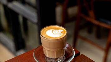 A glass of coffee with latte art on a wooden table.