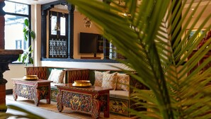 Un interior tradicional con un conjunto de sofás, mesas ornamentadas y lámparas colgantes.