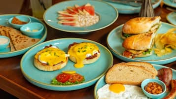 Un bufé de desayuno con una variedad de platos, incluyendo huevos, tocino, tostadas y sándwiches.