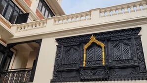 Un edificio con balcón, una puerta decorativa en negro y dorado, y un cielo despejado.
