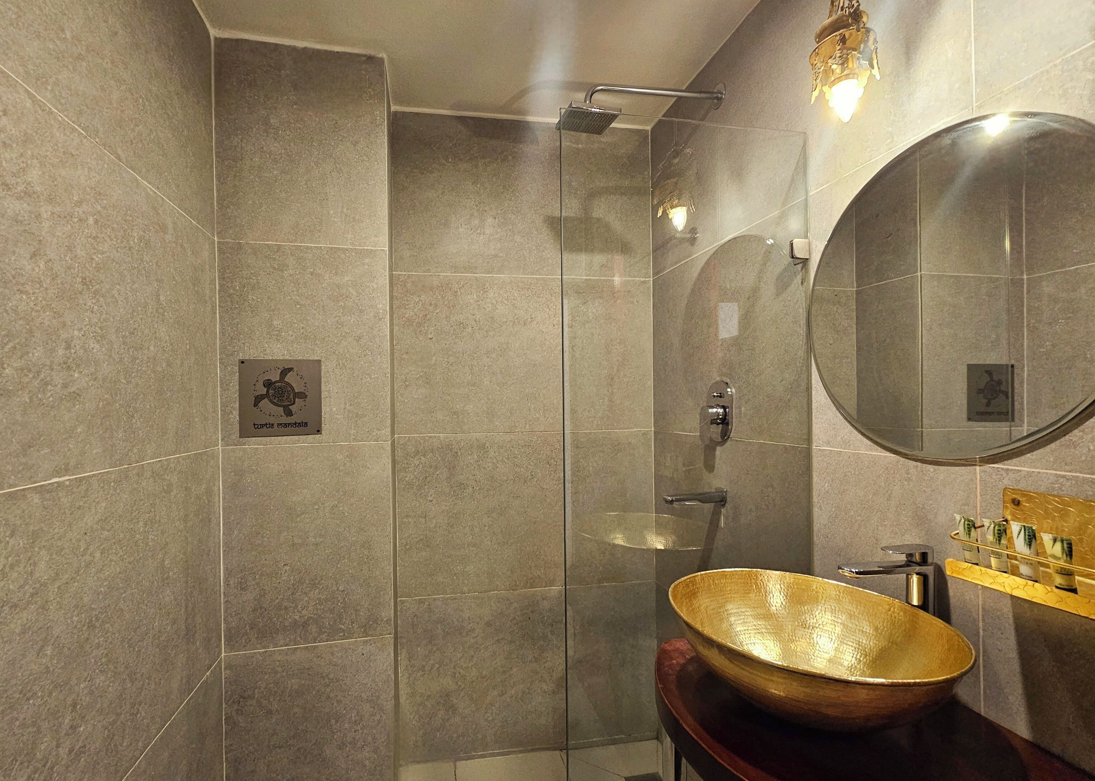 A modern bathroom with a glass shower enclosure, a round mirror, and a wooden bowl sink.