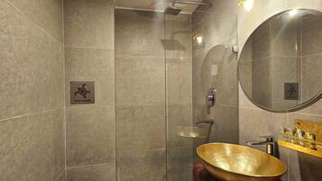 A modern bathroom with a glass shower enclosure, a round mirror, and a wooden bowl sink.