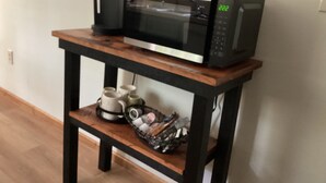 A microwave on a wooden table with a shelf below holding a coffee maker and mugs. - Raystown Lake getaway <br>3 bedroom 2 bath<br> (Huntingdon)