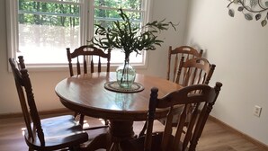 A dining table with six wooden chairs, a vase with green plants, and a decorative wall piece. - Raystown Lake getaway <br>3 bedroom 2 bath<br> (Huntingdon)