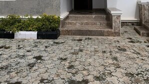 A two-story house with a tiled roof, a front entrance with steps, and a small garden area. - Qeesh Quintessential Apartments (Jos)