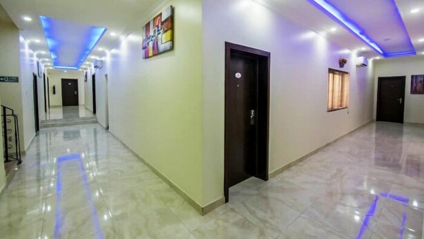 A hallway with a marble floor, blue LED lighting, and a door with a keycard lock. - Qeesh Quintessential Apartments (Jos)