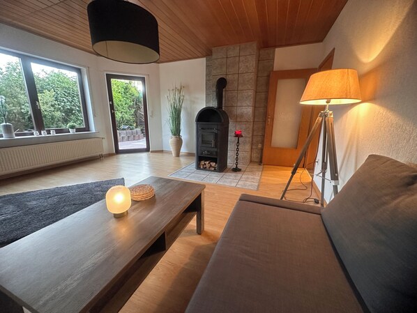 A modern living room with a fireplace, a sofa, a coffee table, and a lamp. - Ferienwohnung Elly 3 km vom Diemelradweg (Liebenau)