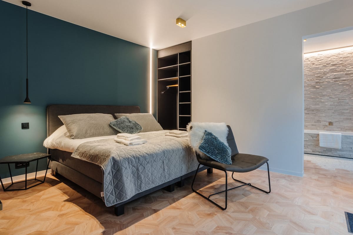 Un dormitorio moderno con cama, una silla, un escritorio y un armario empotrado.