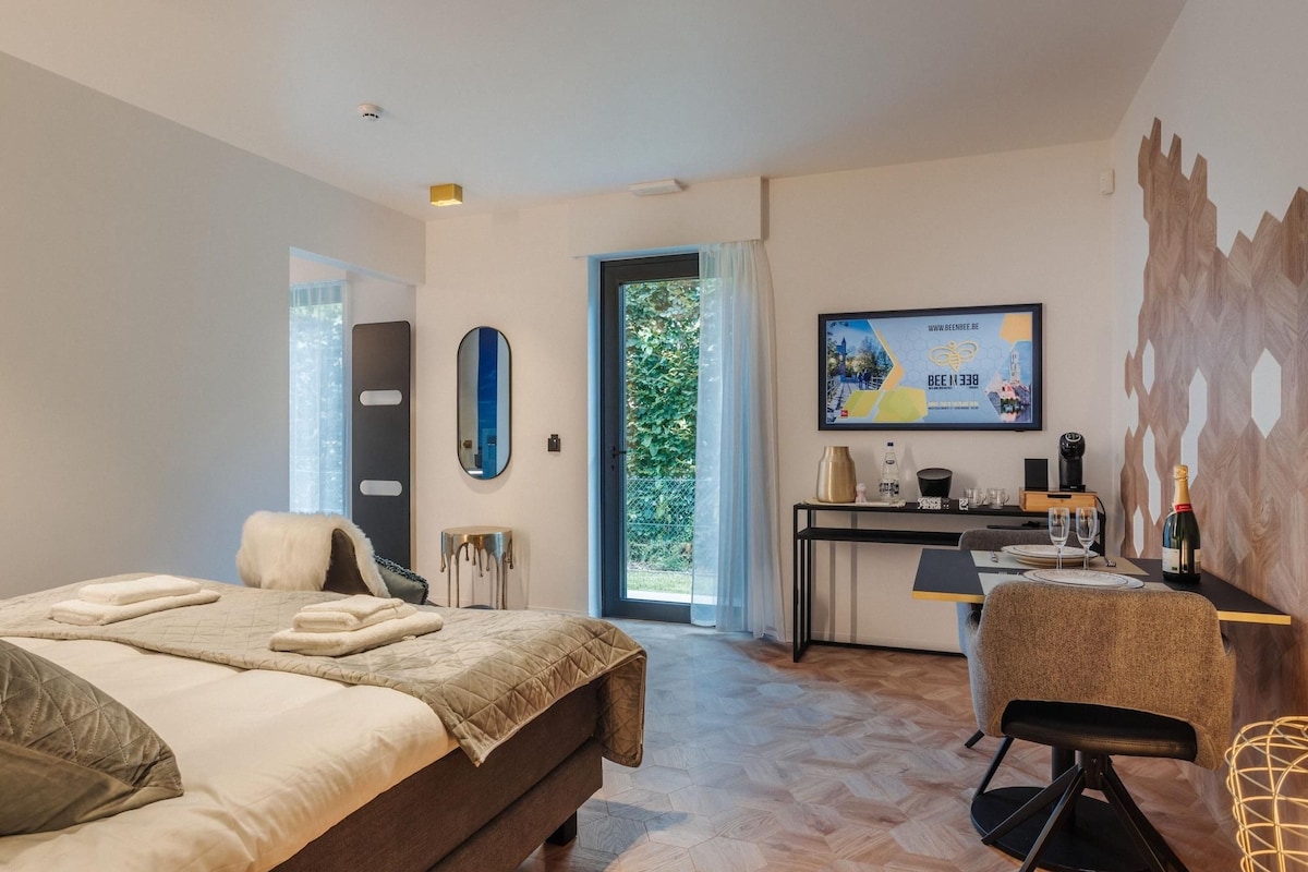 A modern hotel room with a bed, a desk, a chair, a television, and a view of the outdoors.