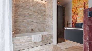 Une salle de bain moderne avec un mur en pierre, une baignoire et un sol carrelé.