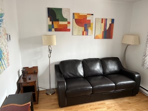 A living room with a black leather sofa, two floor lamps, and abstract wall art. - Spacious 3-bedroom apartment in charming Montréal with WiFi, AC, close to Metro (Montréal)