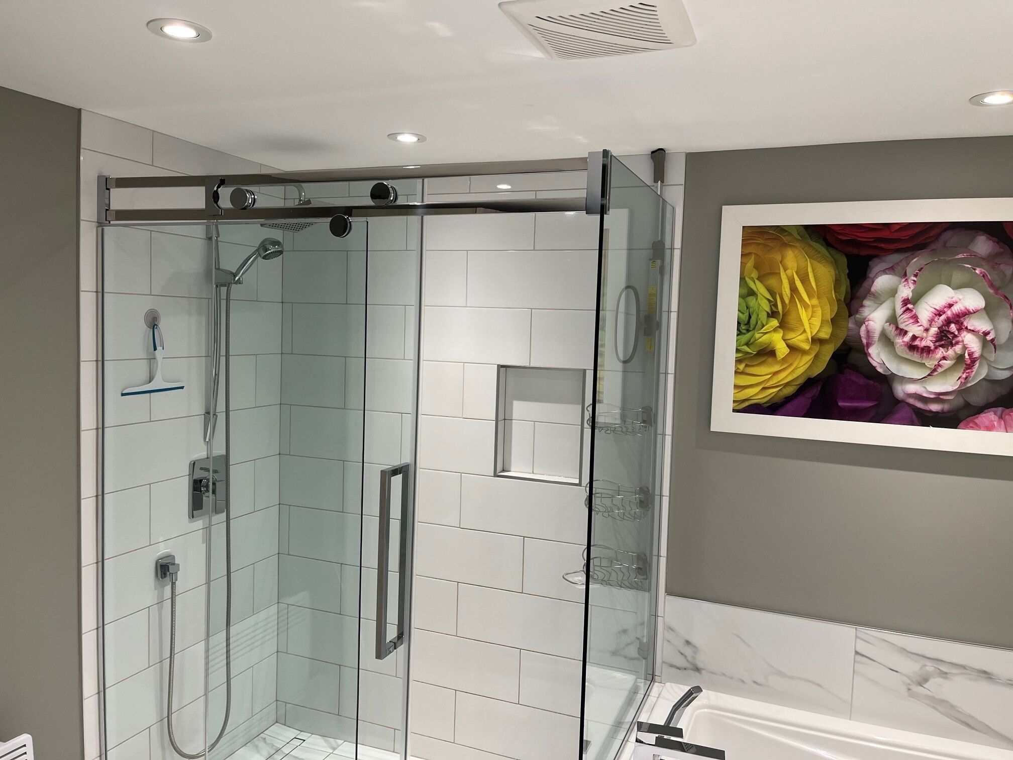 A modern bathroom with a glass-enclosed shower, a white bathtub, and a marble backsplash.