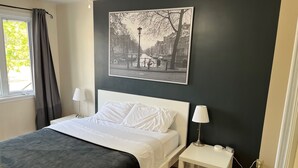 A neatly arranged bedroom with a bed, bedside tables, and a wall-mounted picture.