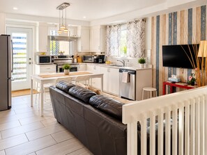 A modern kitchen with white cabinetry, stainless steel appliances, and a dining area with a white table and leather seating. - Spacious 3-bedroom apartment in charming Montréal with WiFi, AC, close to Metro (Montréal)