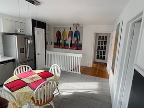 A compact kitchen with modern appliances, a dining area with a table and chairs, and a hallway leading to a door. - Spacious 3-bedroom apartment in charming Montréal with WiFi, AC, close to Metro (Montréal)