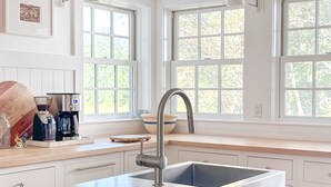 Una cocina moderna con una isla central, pileta de acero inoxidable y una lámpara colgante.