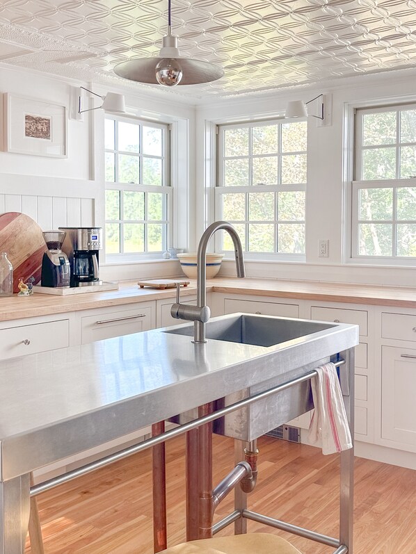 A modern kitchen with a central island, stainless steel sink, and a pendant light. - Apres-Ski House: 20 min to Sunday River and Steam Room (Bryant Pond)