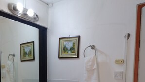 Un baño con un lavabo blanco, un espejo, un perchero para toallas y un cuadro en la pared.