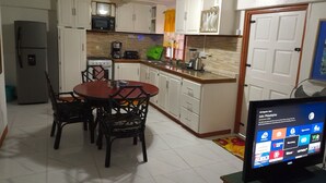Cocina compacta con gabinetes blancos, microondas, estufa y comedor con mesa y sillas.