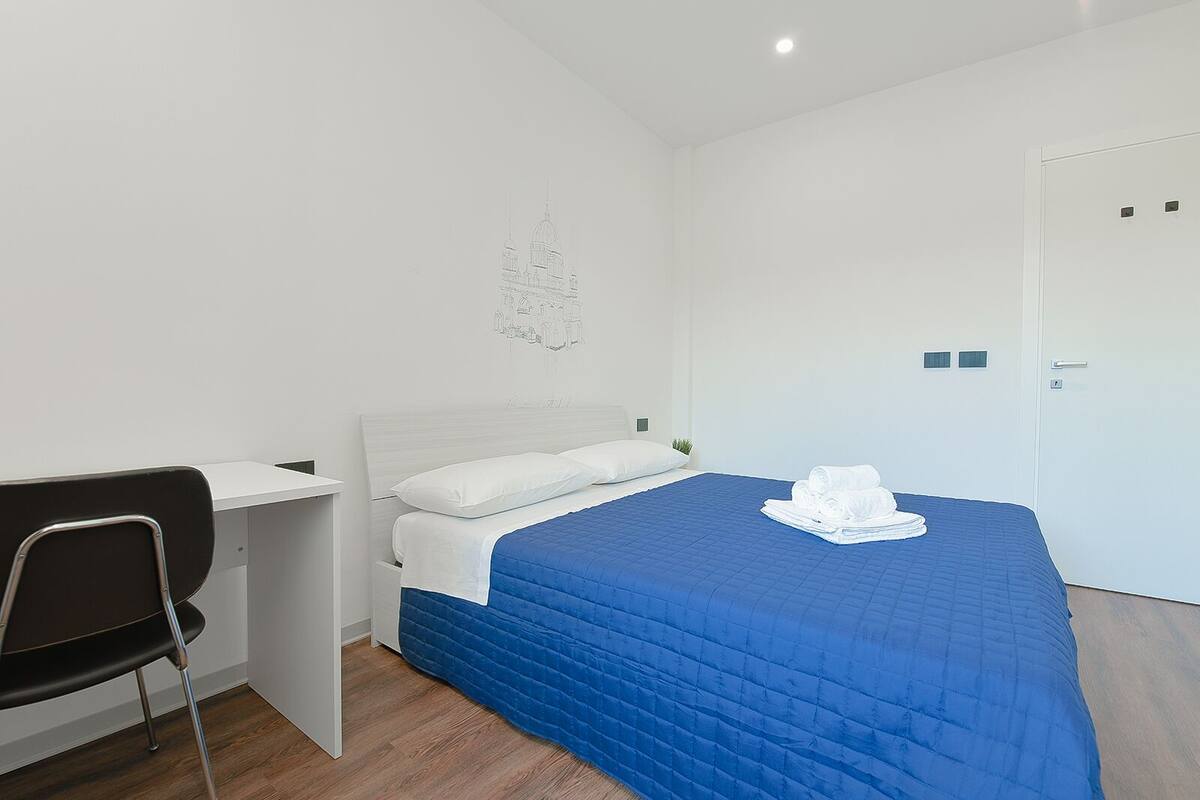 Ein Hotelzimmer mit Bett, Schreibtisch und Stuhl.