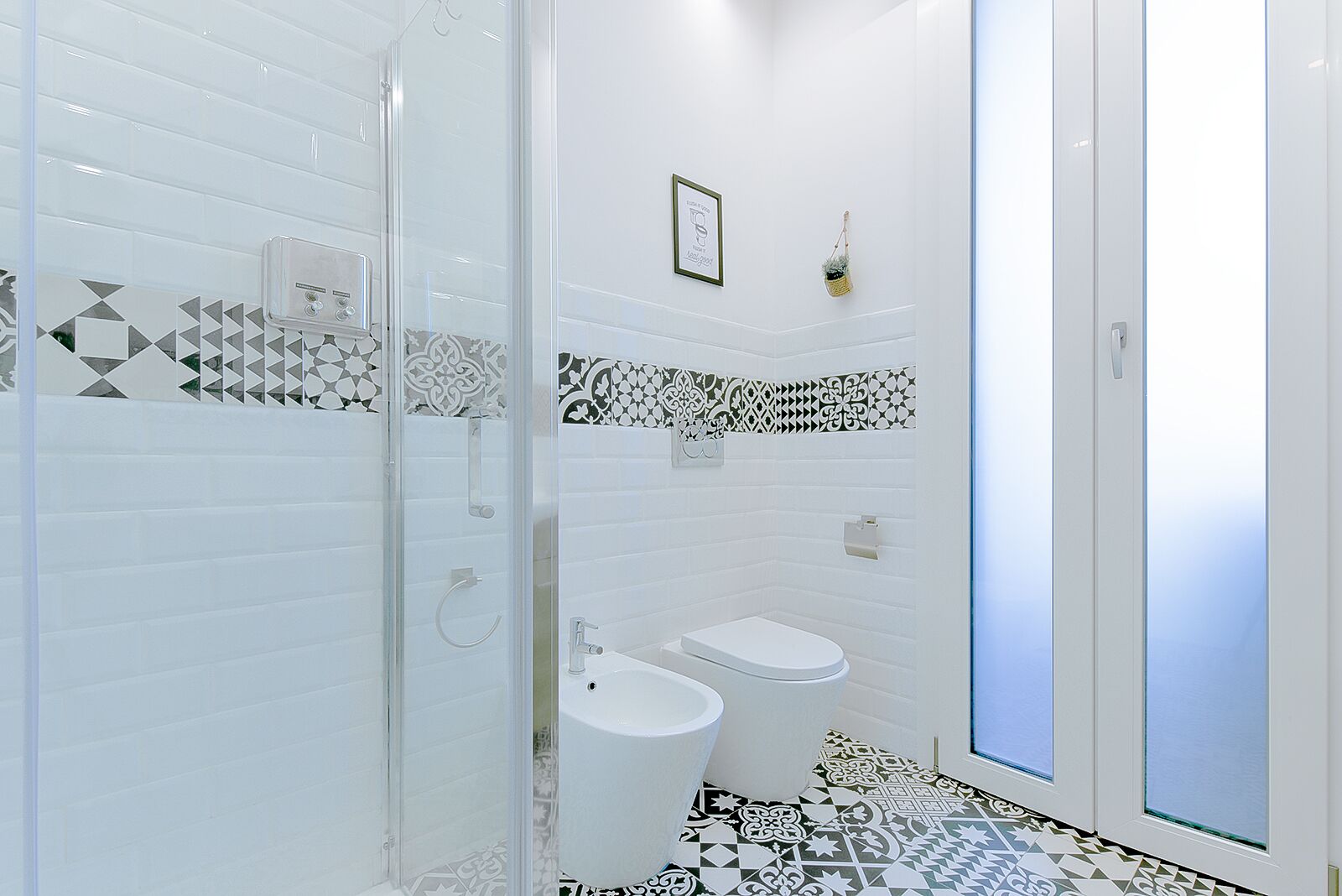 A modern bathroom with a glass shower enclosure, a toilet, and a bidet.