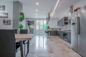 A modern kitchen with a dining area, featuring a marble floor, stainless steel appliances, and a view through the glass doors. - Alle Porte Del Centro (Reggio nell'Emilia)