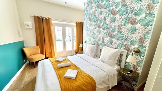 A hotel room with a bed, a chair, a bedside table, and a window with curtains. - Guesthouse close to Disney (Montevrain)